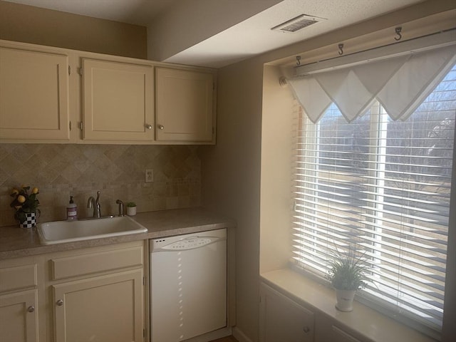 kitchen featuring a sink, visible vents, decorative backsplash, and white dishwasher