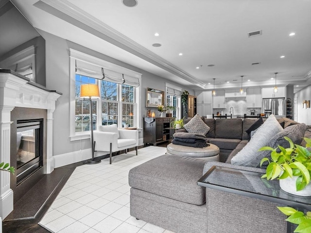 living area featuring ornamental molding, a fireplace, visible vents, and recessed lighting