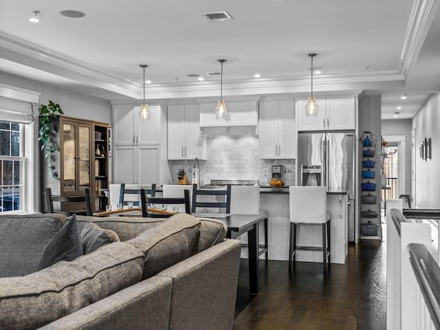 living room featuring a wealth of natural light, visible vents, dark wood-style flooring, and ornamental molding