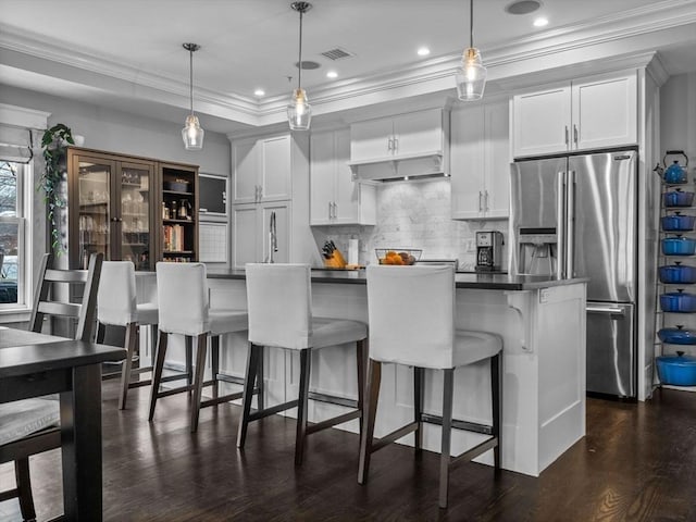 kitchen featuring stainless steel refrigerator with ice dispenser, dark countertops, white cabinetry, and pendant lighting