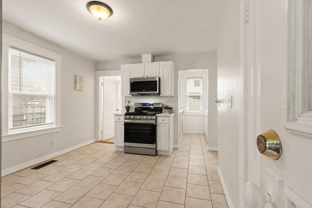 kitchen featuring white cabinetry, appliances with stainless steel finishes, decorative backsplash, and light tile patterned floors