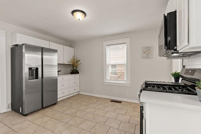 kitchen with tasteful backsplash, appliances with stainless steel finishes, light tile patterned floors, and white cabinets