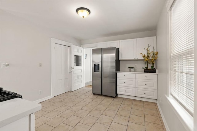 kitchen featuring white cabinetry, stainless steel fridge, and light tile patterned floors