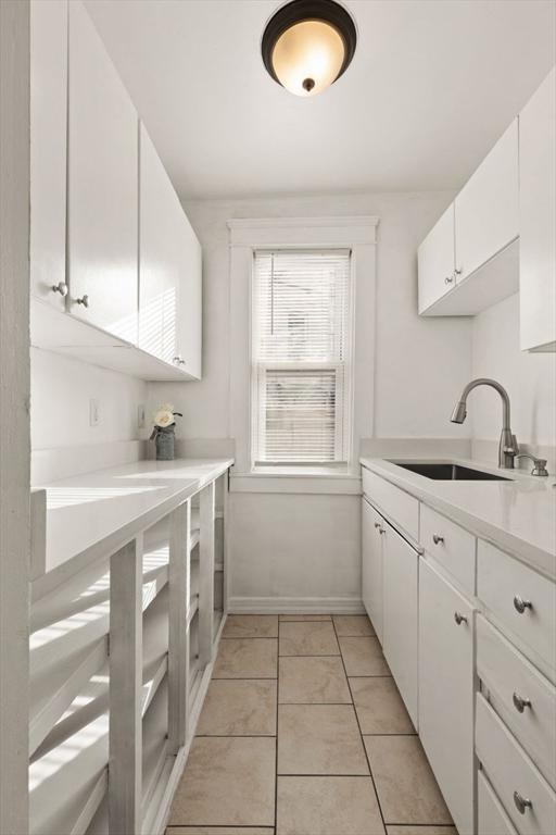 kitchen featuring light tile patterned flooring, sink, and white cabinets