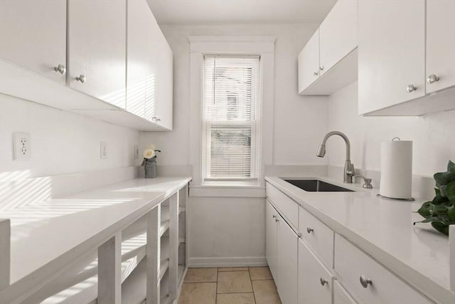 kitchen with light tile patterned floors, sink, and white cabinets