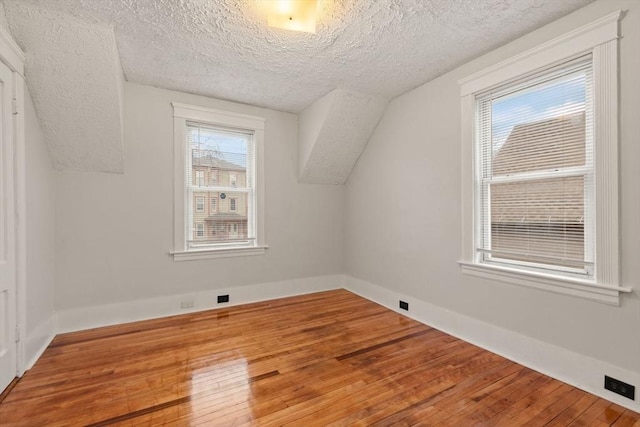 bonus room featuring hardwood / wood-style floors, vaulted ceiling, and a textured ceiling