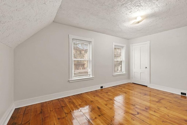 bonus room featuring hardwood / wood-style flooring, lofted ceiling, and a textured ceiling