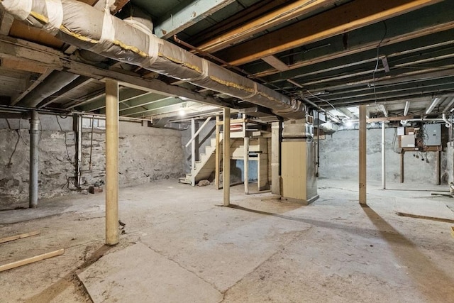 basement featuring electric panel and heating unit