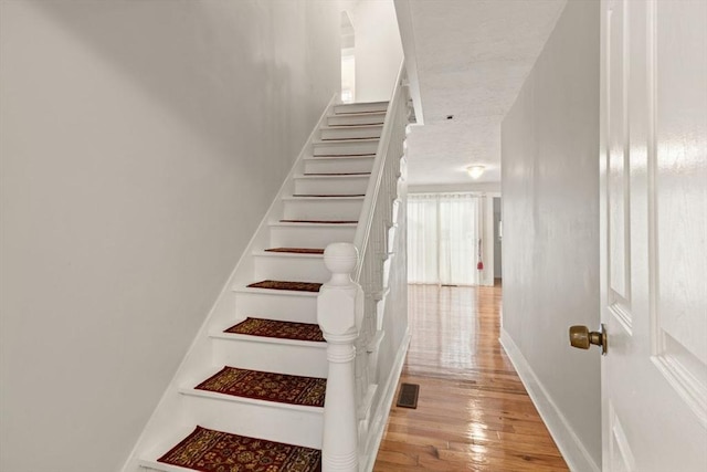 staircase with hardwood / wood-style floors