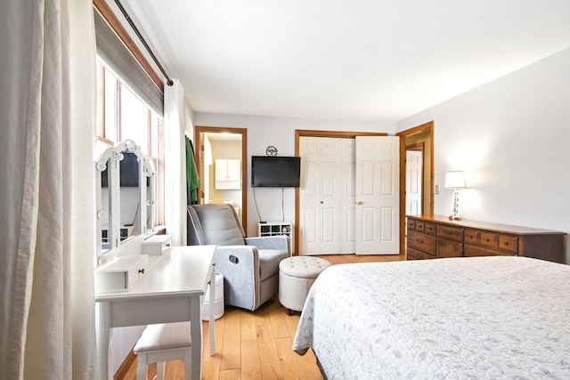 bedroom with light wood finished floors, ensuite bathroom, and a closet