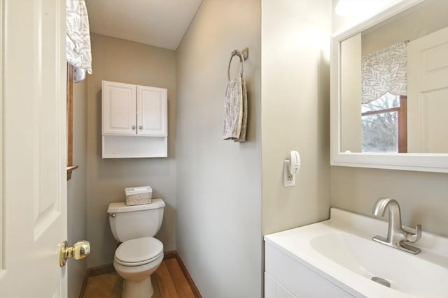 bathroom featuring toilet, vanity, baseboards, and wood finished floors