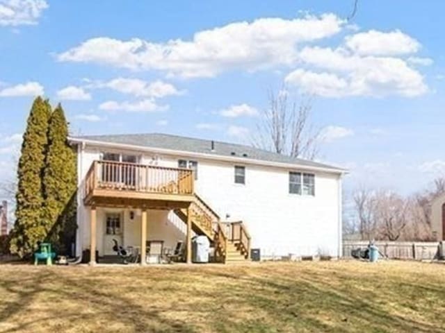 back of property featuring stairway, a lawn, a wooden deck, and fence