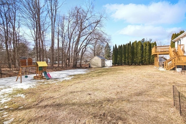 view of yard featuring an outbuilding, fence, a shed, a playground, and stairs