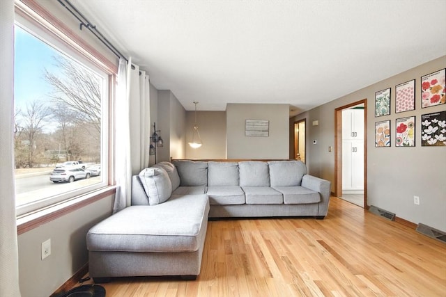 living room featuring baseboards, visible vents, and light wood-type flooring