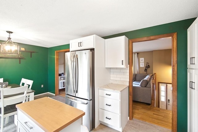 kitchen featuring white cabinetry, decorative backsplash, freestanding refrigerator, and a center island