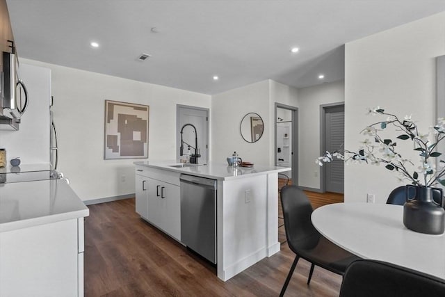 kitchen with dark hardwood / wood-style floors, appliances with stainless steel finishes, white cabinets, and a center island with sink