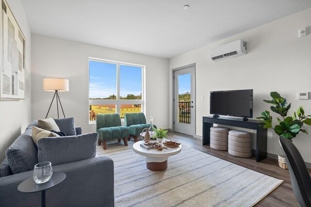 living area featuring baseboards, wood finished floors, and a wall unit AC