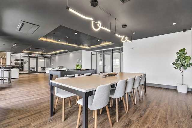 dining area with a raised ceiling, wood finished floors, baseboards, and french doors