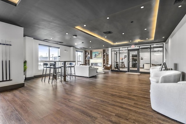 living room with a raised ceiling, recessed lighting, wood finished floors, and baseboards