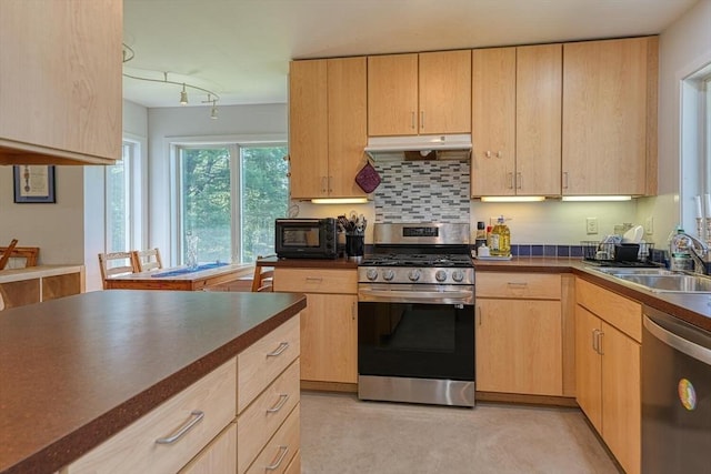 kitchen featuring stainless steel appliances, a sink, light brown cabinets, and under cabinet range hood