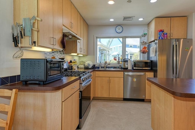 kitchen with appliances with stainless steel finishes, a sink, dark countertops, under cabinet range hood, and recessed lighting