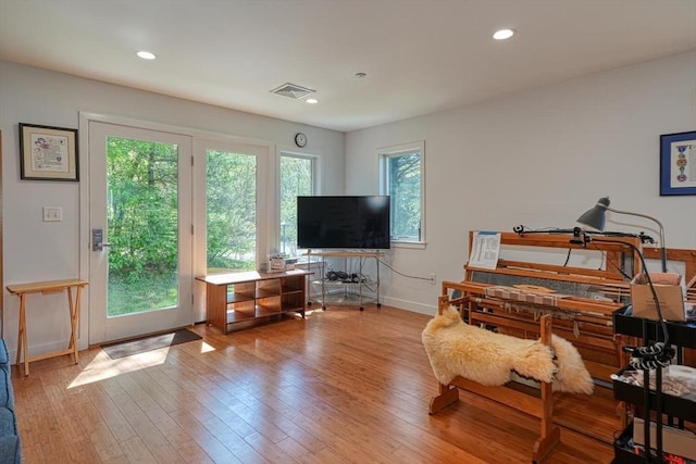 living area with baseboards, hardwood / wood-style flooring, and recessed lighting