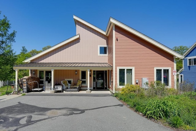 rear view of property with a porch, a standing seam roof, and metal roof
