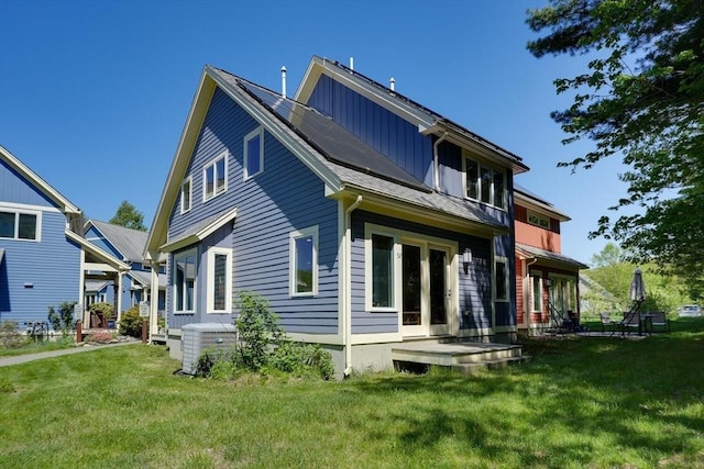rear view of house featuring central AC, a lawn, and board and batten siding