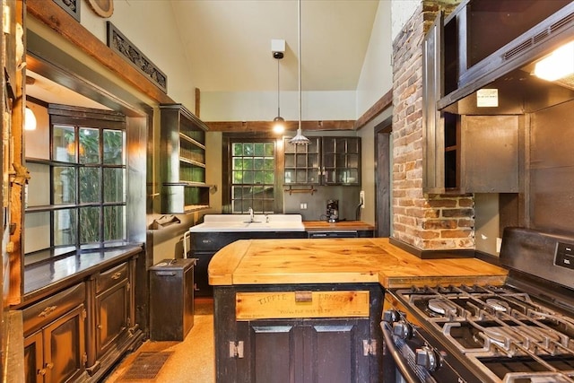 100 Center St, Dennis, MA 02660 - kitchen with stainless steel range with gas stovetop, wooden counters, hanging light fixtures, under cabinet range hood, and dark brown cabinetry