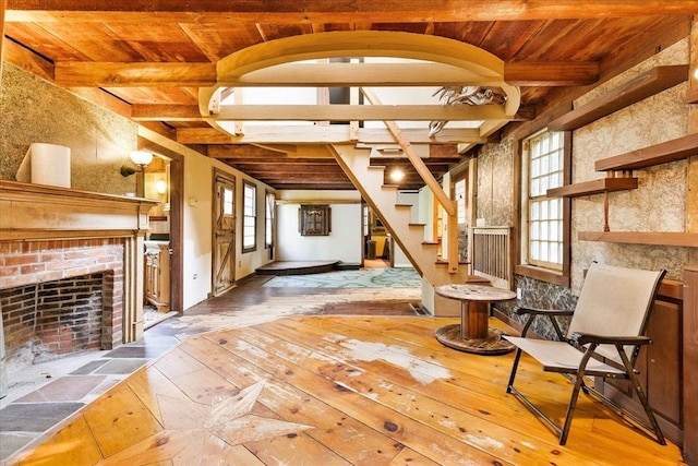 100 Center St, Dennis, MA 02660 - living area with hardwood / wood-style flooring, wood ceiling with exposed beams, stairway, healthy amount of natural light, and a brick fireplace