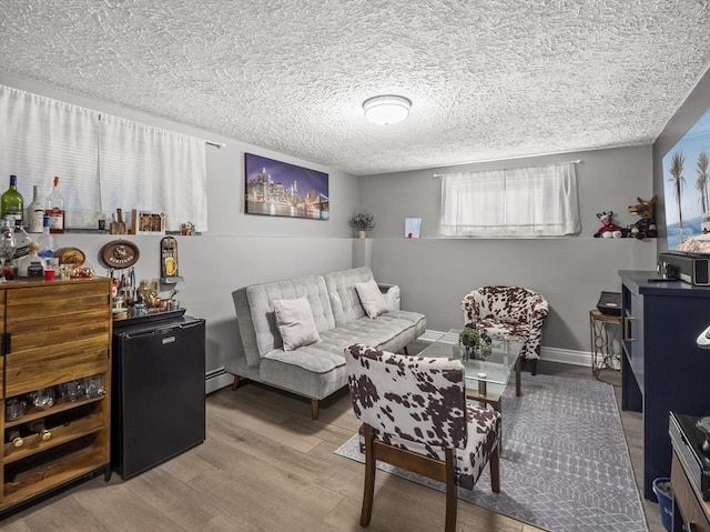 living room featuring a textured ceiling, a baseboard heating unit, and hardwood / wood-style flooring