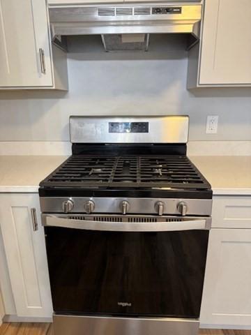 305 Pine St Unit 18, Lowell, MA 01851 - room details with light wood-type flooring, white cabinetry, under cabinet range hood, light countertops, and gas stove