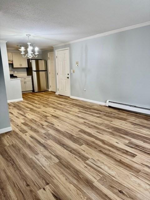 305 Pine St Unit 18, Lowell, MA 01851 - unfurnished living room with wood finished floors, ornamental molding, a chandelier, baseboard heating, and baseboards