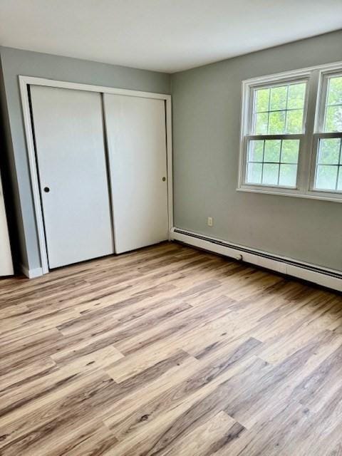 305 Pine St Unit 18, Lowell, MA 01851 - unfurnished bedroom featuring a baseboard radiator, a closet, and wood finished floors