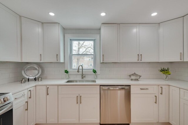 kitchen with appliances with stainless steel finishes, white cabinetry, and a sink