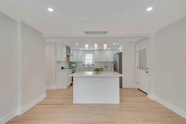 kitchen with a kitchen island, light countertops, white cabinetry, pendant lighting, and backsplash