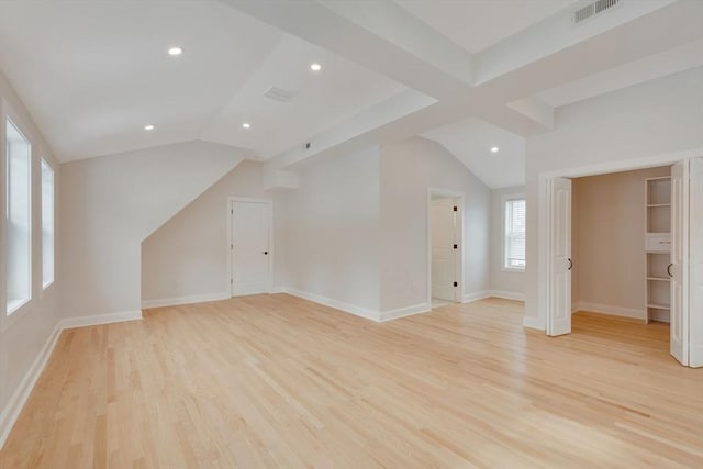 additional living space featuring light wood-style floors, visible vents, and vaulted ceiling with beams