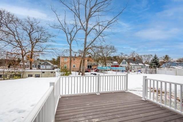 snow covered deck featuring a residential view and fence