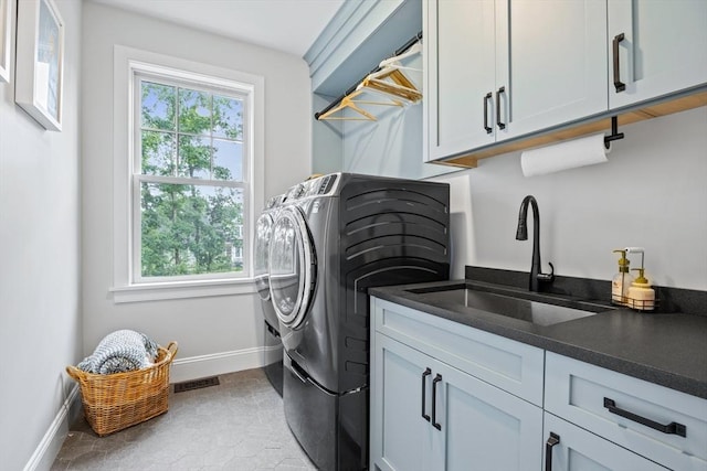 washroom featuring visible vents, baseboards, cabinet space, a sink, and washing machine and dryer