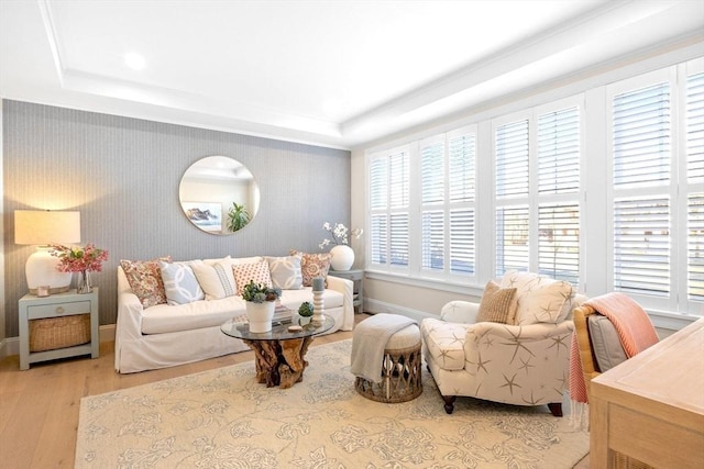 living room featuring a tray ceiling, baseboards, and light wood-style flooring