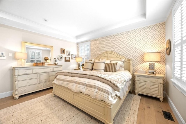 bedroom featuring a tray ceiling, visible vents, baseboards, and wallpapered walls