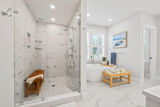 bathroom with recessed lighting, a shower stall, a freestanding bath, and marble finish floor