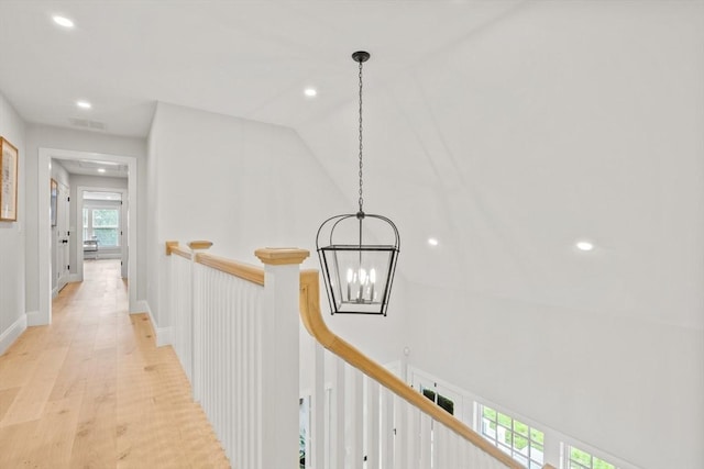 hallway featuring visible vents, baseboards, light wood-style flooring, recessed lighting, and an upstairs landing