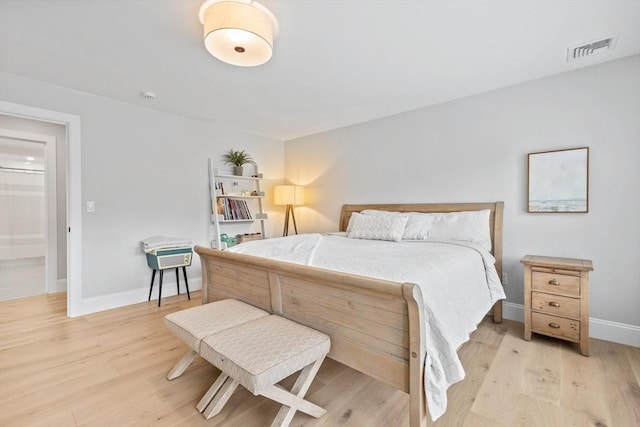 bedroom with baseboards, visible vents, and light wood finished floors