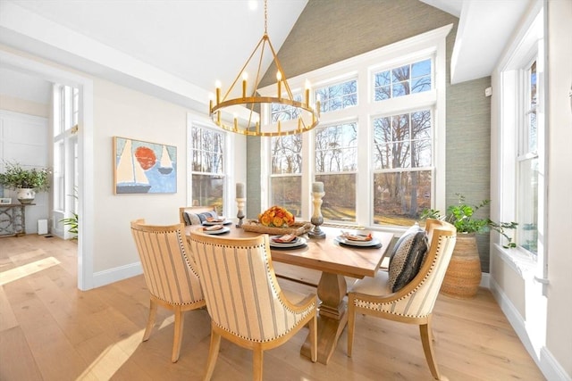 dining space with high vaulted ceiling, an inviting chandelier, baseboards, and light wood-style floors