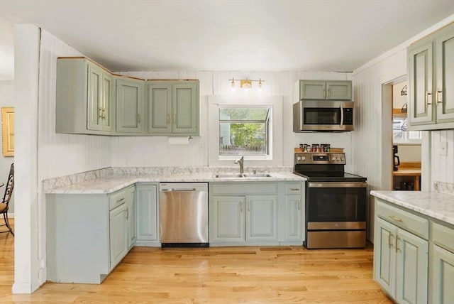 130 Franklin St, Milford, NH 03055 - kitchen featuring appliances with stainless steel finishes, a sink, green cabinets, and light wood-style flooring
