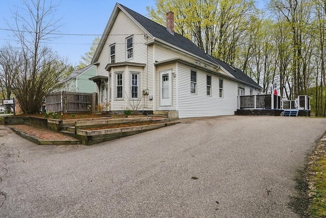 130 Franklin St, Milford, NH 03055 - view of front of house featuring a chimney, fence, and roof with shingles