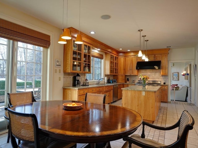 kitchen with dishwasher, light tile patterned floors, tasteful backsplash, decorative light fixtures, and a kitchen island