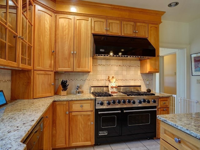 kitchen with light tile patterned flooring, double oven range, light stone countertops, and tasteful backsplash