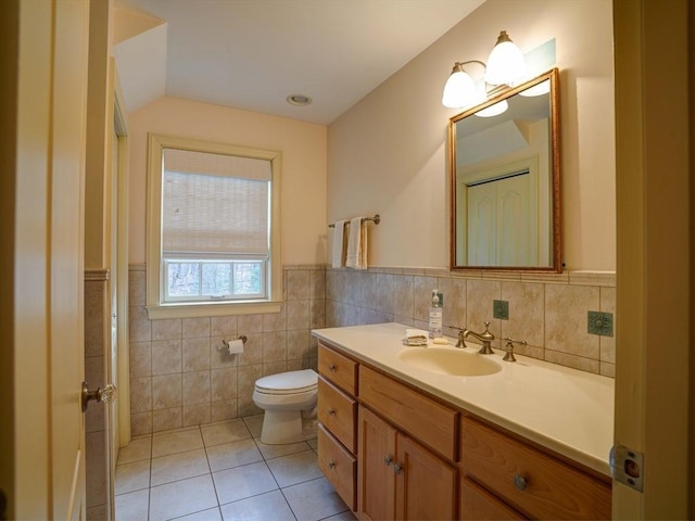 bathroom featuring tile patterned floors, vanity, toilet, and tile walls